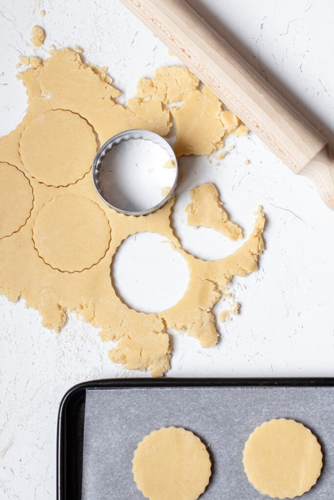 Rolling out shortbread biscuit dough and cutting out round biscuits
