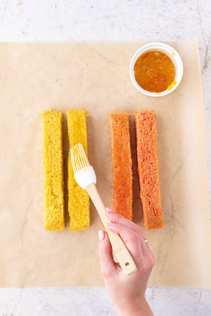 Brushing battenberg sponge with jam