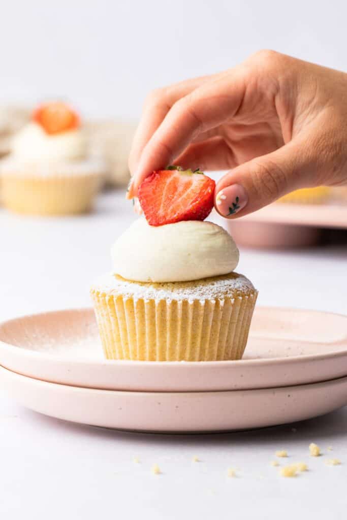 Placing a strawberry on a Victoria Sponge Cupcake