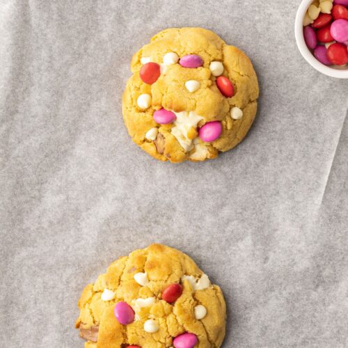 Two thick NYC style chocolate chunk cookies with red and pink Smarties as toppings
