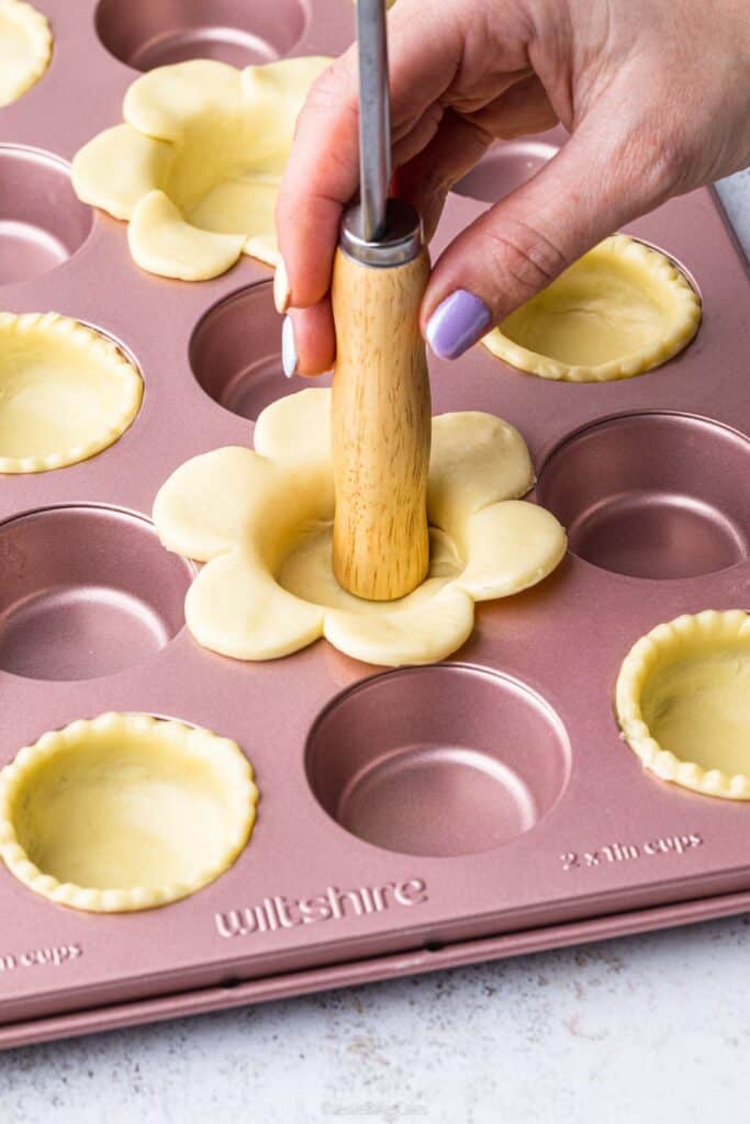 pressing pastry into a baking tin to make flower tartlets