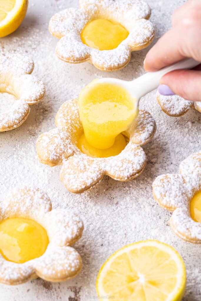 Spooning lemon curd into a shortcrust pastry flower tartlet