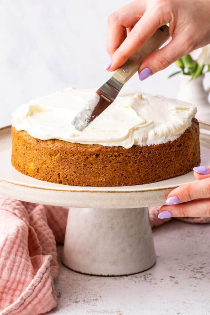 spreading cream cheese frosting onto carrot cake
