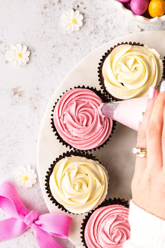 piping the best vanilla buttercream onto chocolate cupcakes