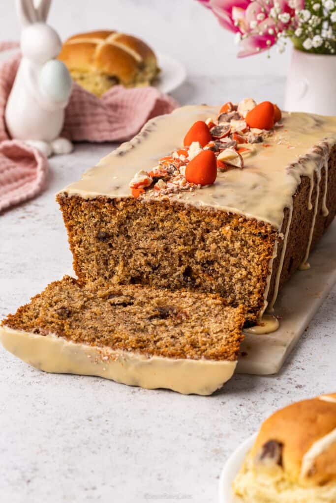 A sticky toffee hot cross loaf cake with a slice cut from it