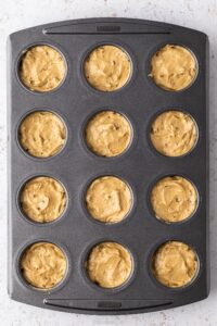 A top down view of a 12 hole muffin tin with Mini Coffee and Walnut Cake mix