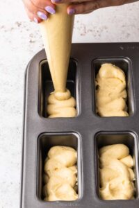 Filling mini loaf tins with cake mixture using a piping bag