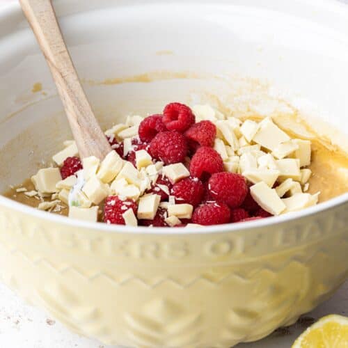 a bowl of blondie mixture with raspberries and white chocolate chunks
