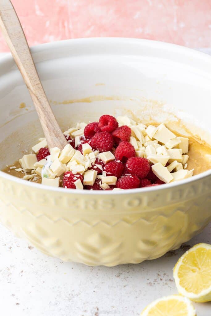 a bowl of blondie mixture with raspberries and white chocolate chunks