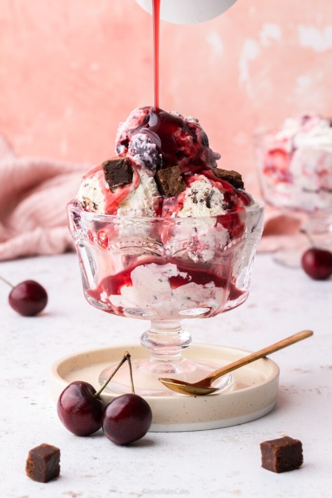 Pouring sour cherry sauce on top of Black forest ice cream with brownie chunks