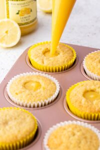 filling a lemon cupcake with lemon curd