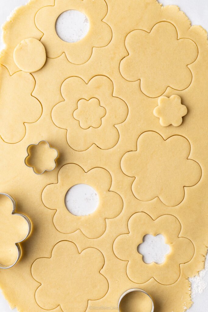 shortbread biscuit dough rolled out with flower shaped cookie cutters