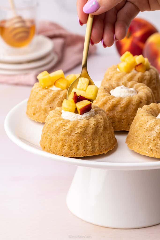 spooning honey soaked peaches on top of mini bundt cakes
