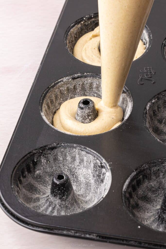 piping cake mixture into a mini bundt cake baking tin