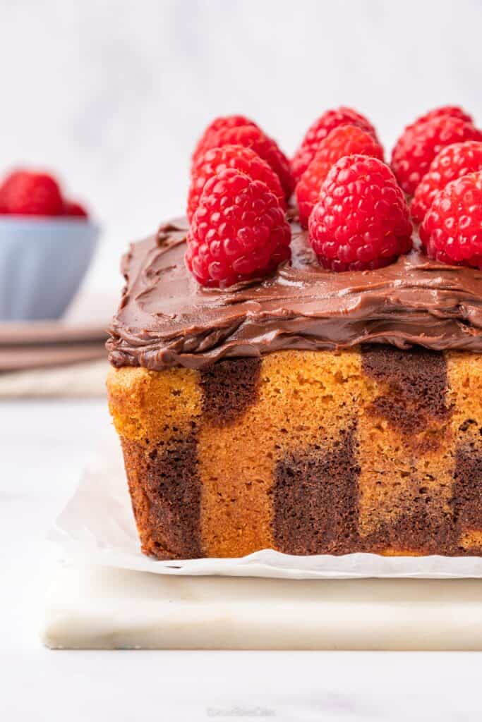 close up of the chocolate marble cake topped with chocolate ganache and fresh raspberries
