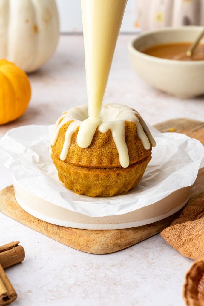 piping white chocolate icing over cakes