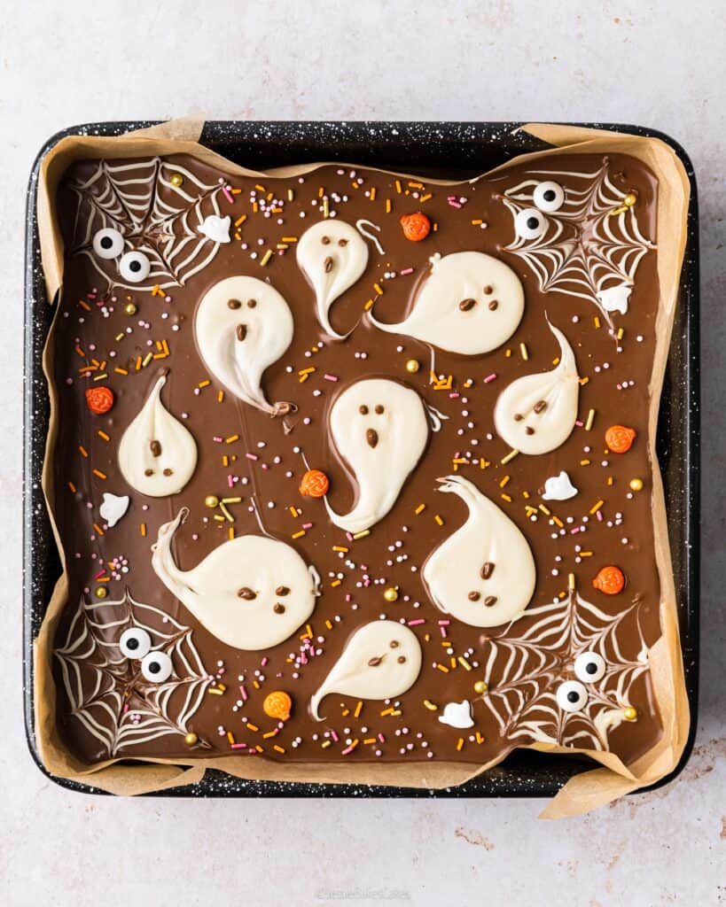 white chocolate spiderwebs and halloween sprinkles on millionaires shortbread