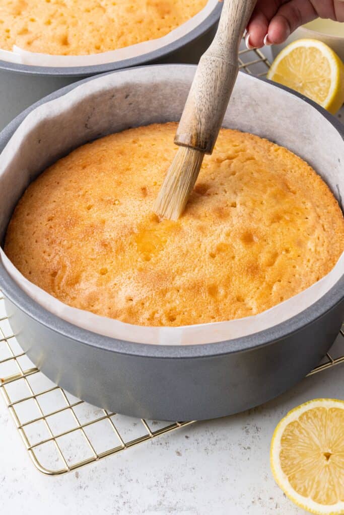brushing lemon sugar syrup onto a cake